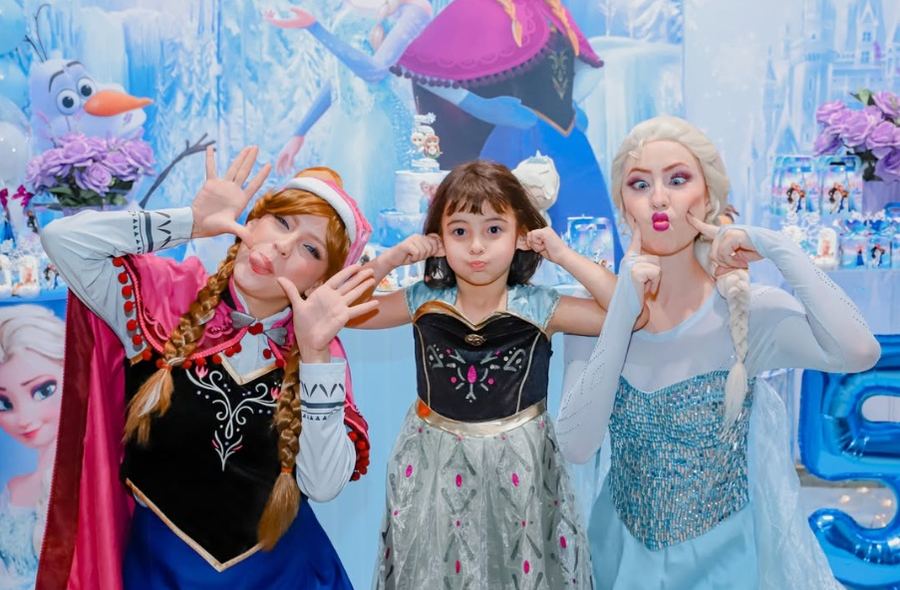 Elsa e Anna fazendo caretas com a aniversariante em festa de Frozen